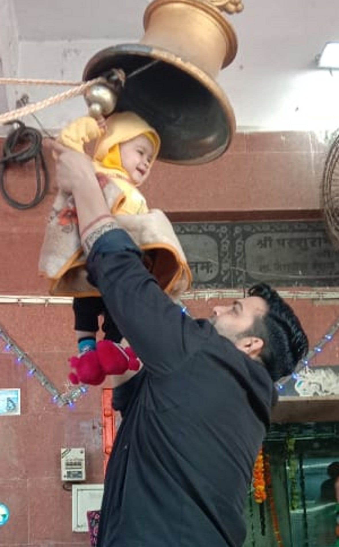 बालैनी के पुरा महादेव मंदिर में जलाभिषेक के बाद बच्ची से घंटा बजवाता पिता बालैनी के पुरा महादेव मंदिर में जलाभिषेक के बाद बच्ची से घंटा बजवाता पिता