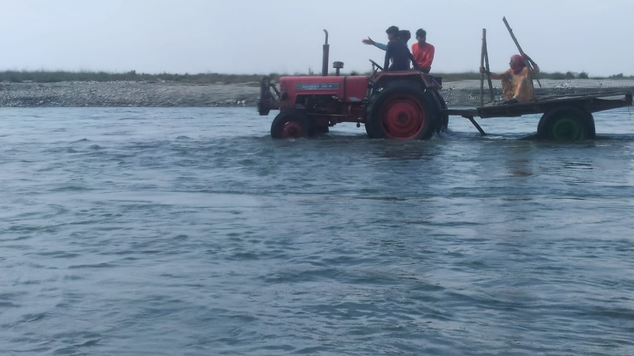 ट्रैक्टर पर बैठ कर यमुना पार करती महिला ट्रैक्टर पर बैठ कर यमुना पार करती महिला