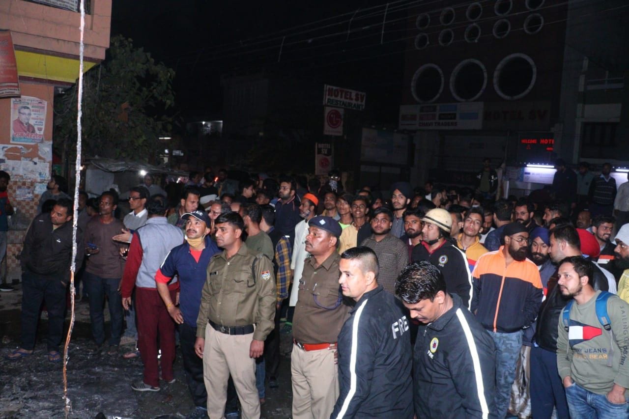 शोरूम में आग लगने के बाद मौके पर जमा भीड़ और पुलिस।