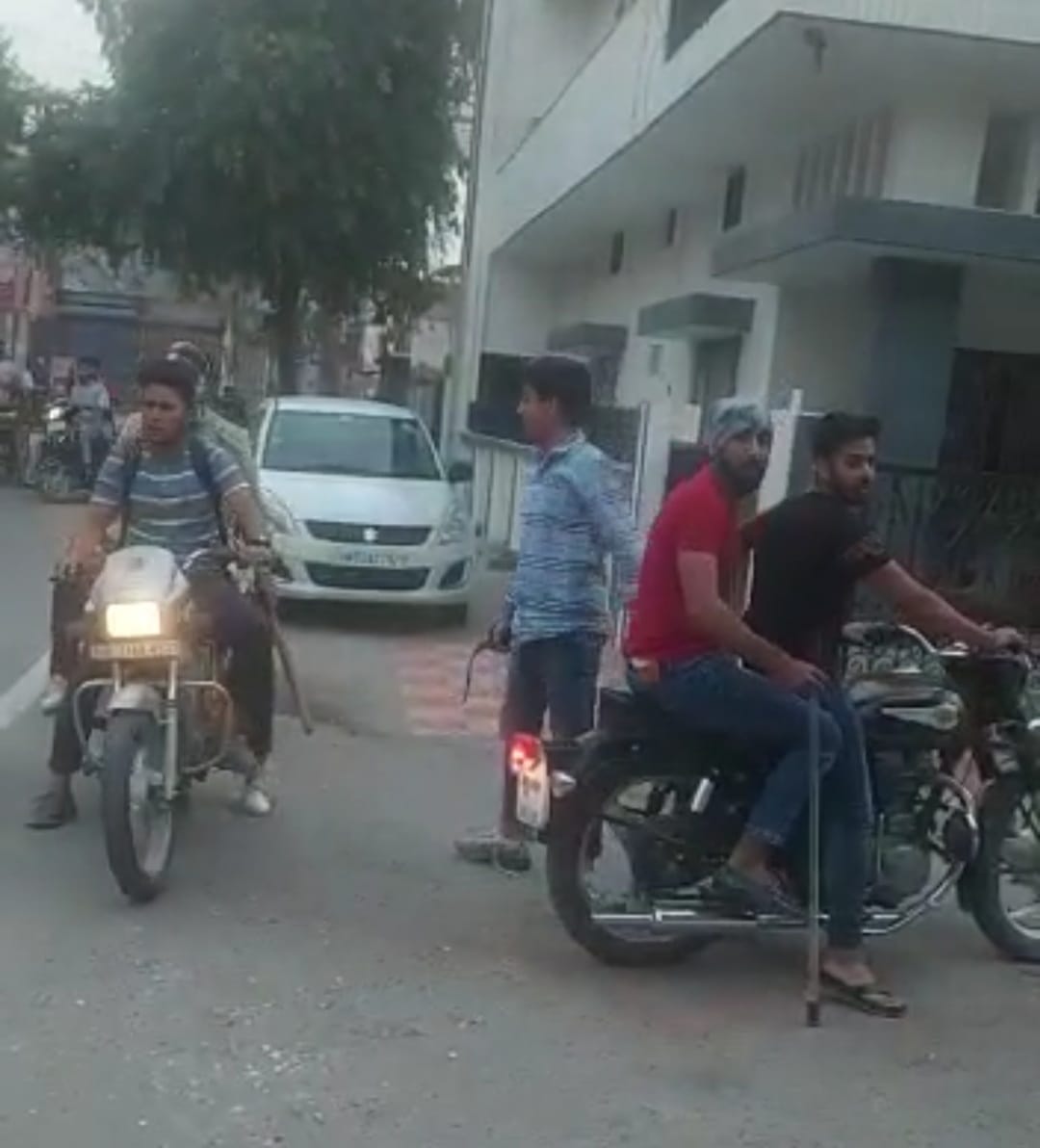 हाथों में लाठी-डंडे लिए बाइक सवार युवक हाथों में लाठी-डंडे लिए बाइक सवार युवक
