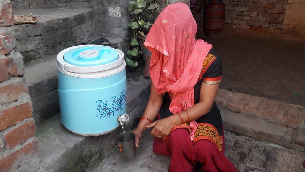 खतौली के गांव शेखपुरा में कैम्पर से पीने के लिए पानी लेते हुए महिला।