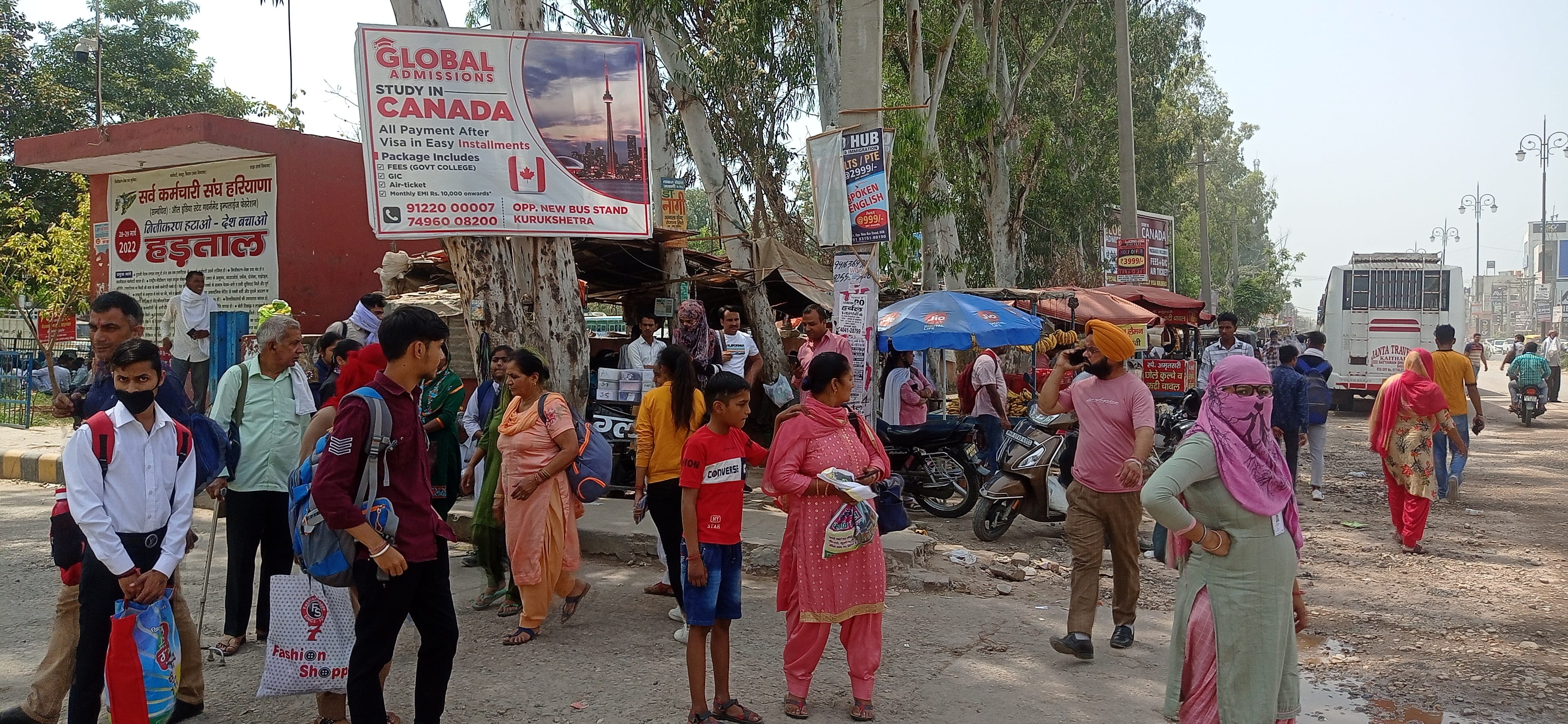 सड़क के किनारे खड़े होकर वाहन का इंतजार करते यात्री।  संवाद