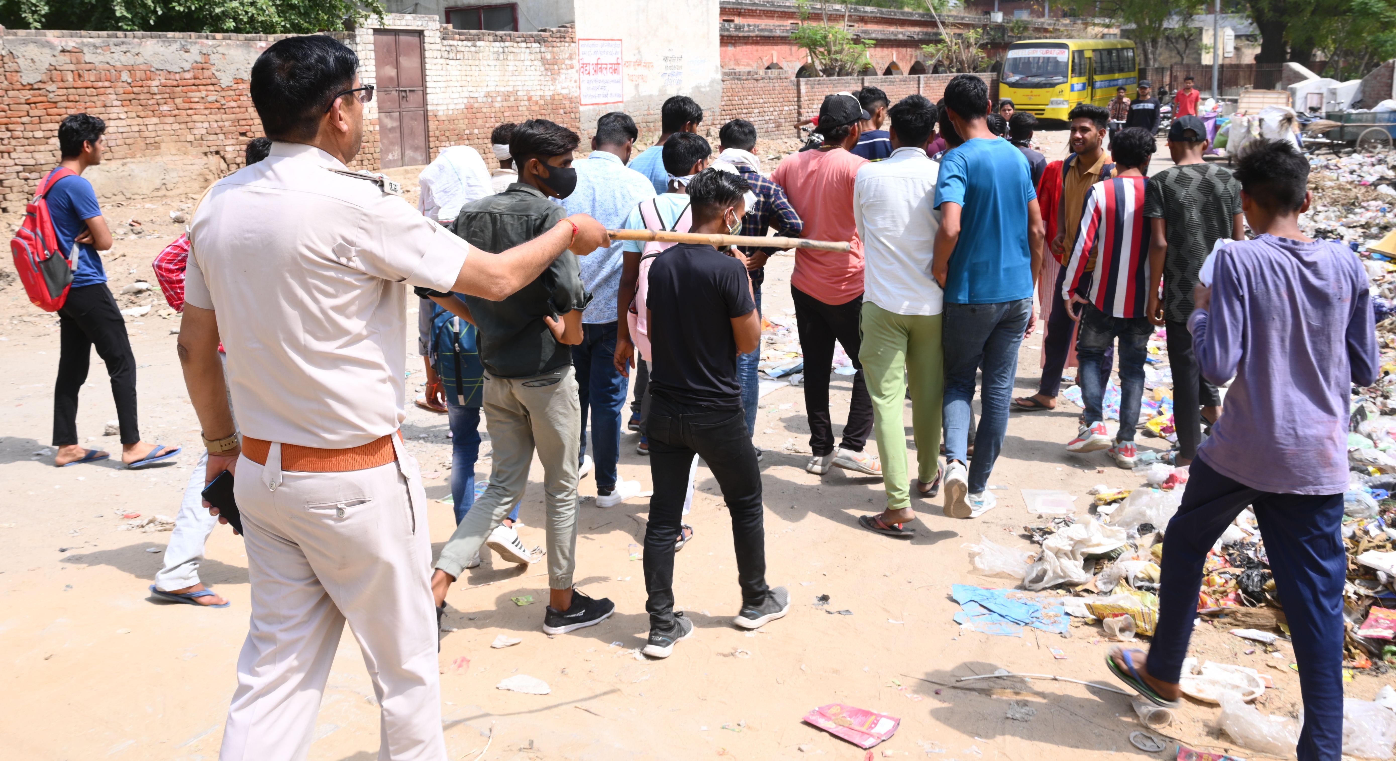 परीक्षा केंद्र के बाहर से युवकों को खदेड़ता पुलिस अधिकारी। संवाद परीक्षा केंद्र के बाहर से युवकों को खदेड़ता पुलिस अधिकारी। संवाद