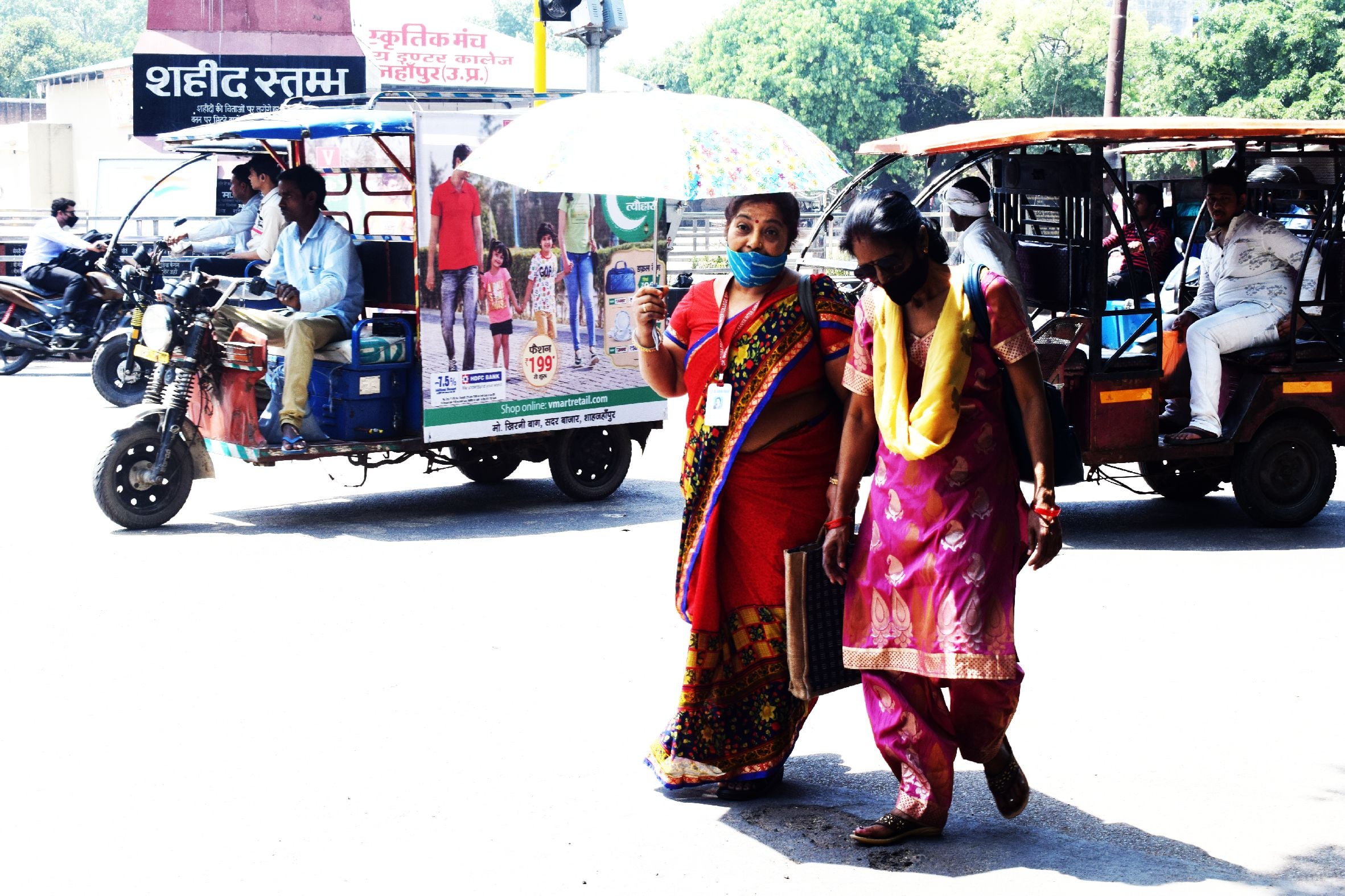 शाहजहांपुर में तेज धूप से बचने के लिए छाता लगाकर जाती महिलाएं । संवाद