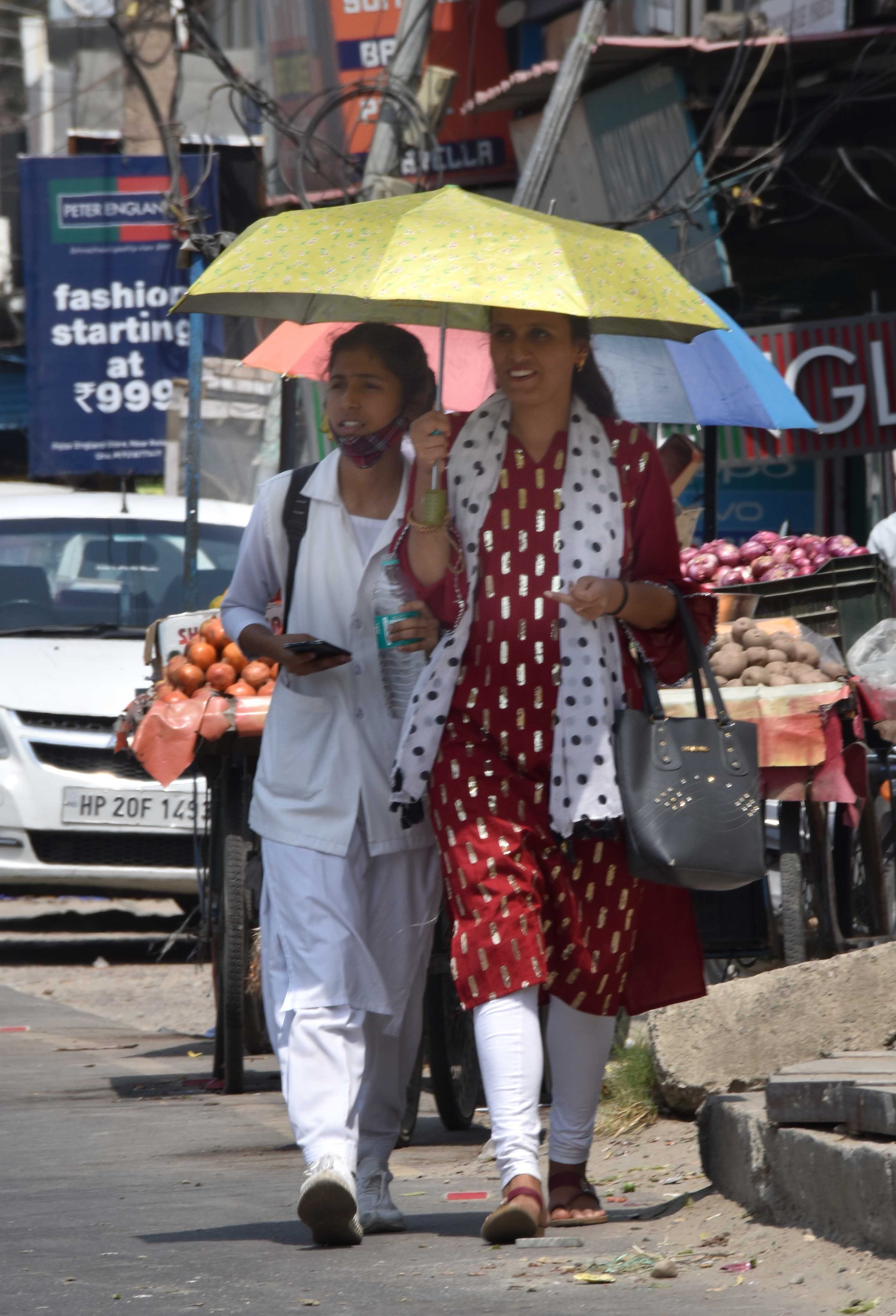 ऊना में तेज गर्मी के दौरान छाता लेकर जाती युवतियां।संवाद ऊना में तेज गर्मी के दौरान छाता लेकर जाती युवतियां।संवाद