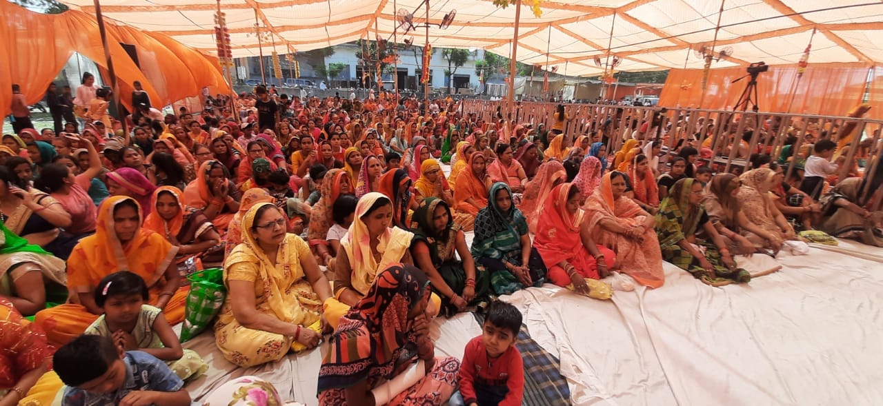 अमीनगर सराय में कथा सुनती महिला श्रद्घालु