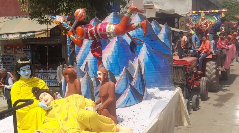 शोभायात्रा में शक्ति लगने के बाद मूर्छित पड़े लक्ष्मण जी और हवा में घूमते हनुमान की झांकी शोभायात्रा में शक्ति लगने के बाद मूर्छित पड़े लक्ष्मण जी और हवा में घूमते हनुमान की झांकी