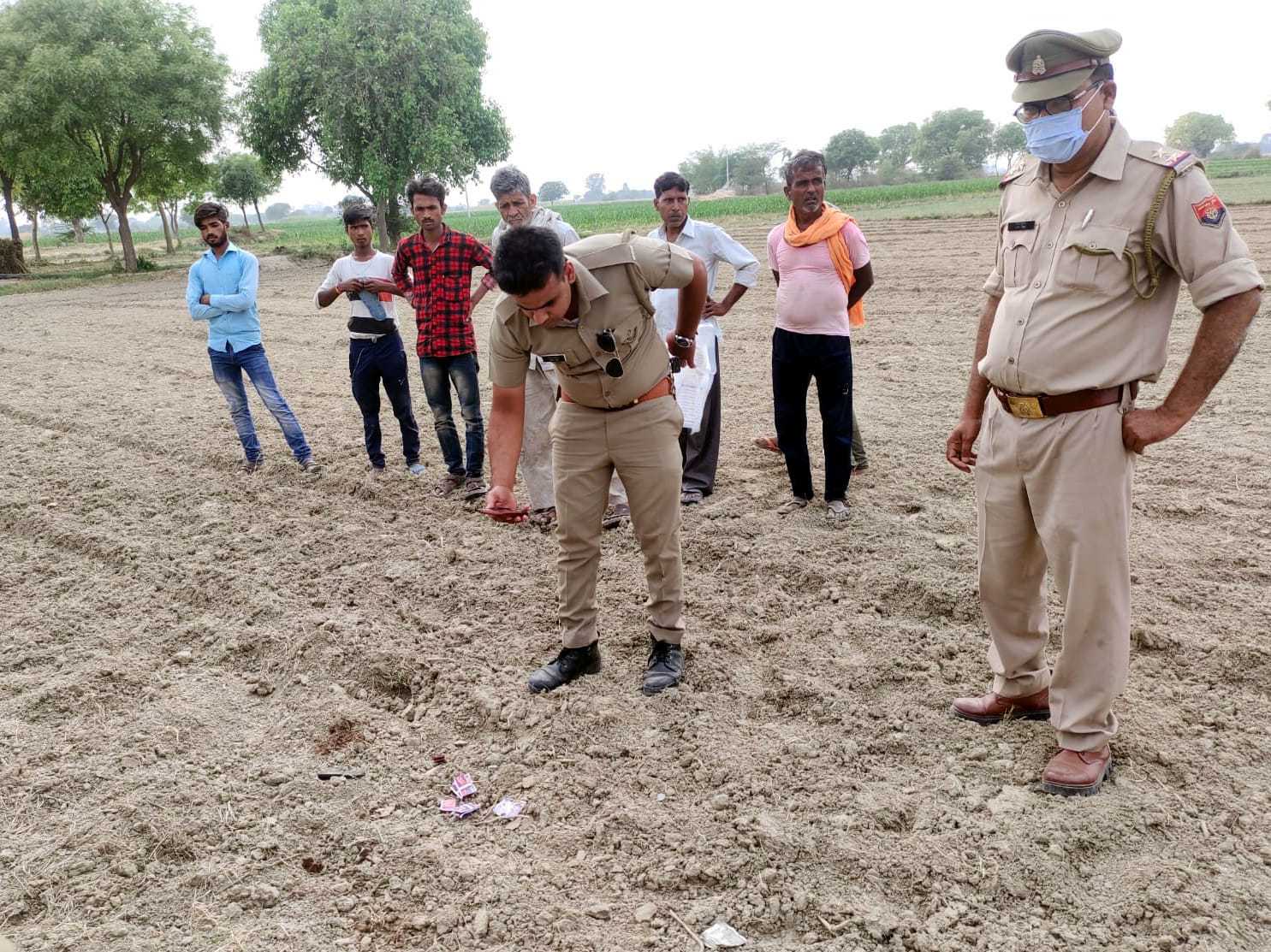 खेत में पड़े खून के छींटे देखते पुलिस कर्मी। संवाद