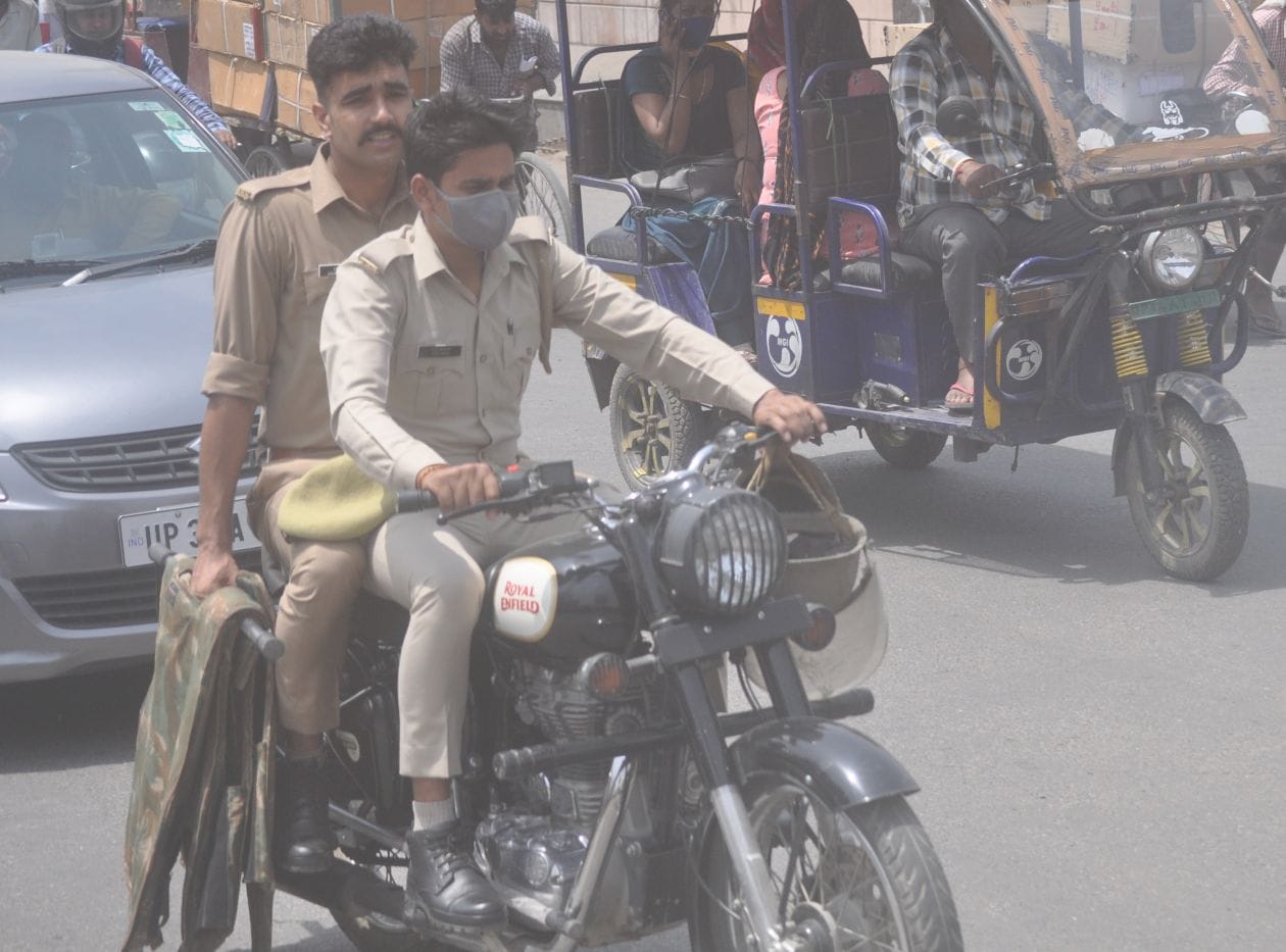 मंगलवार को मेरठ तिराहे पर हेलमेट हाथ में लेकर बूलेट चलाता पुलिसकर्मी । संवाद