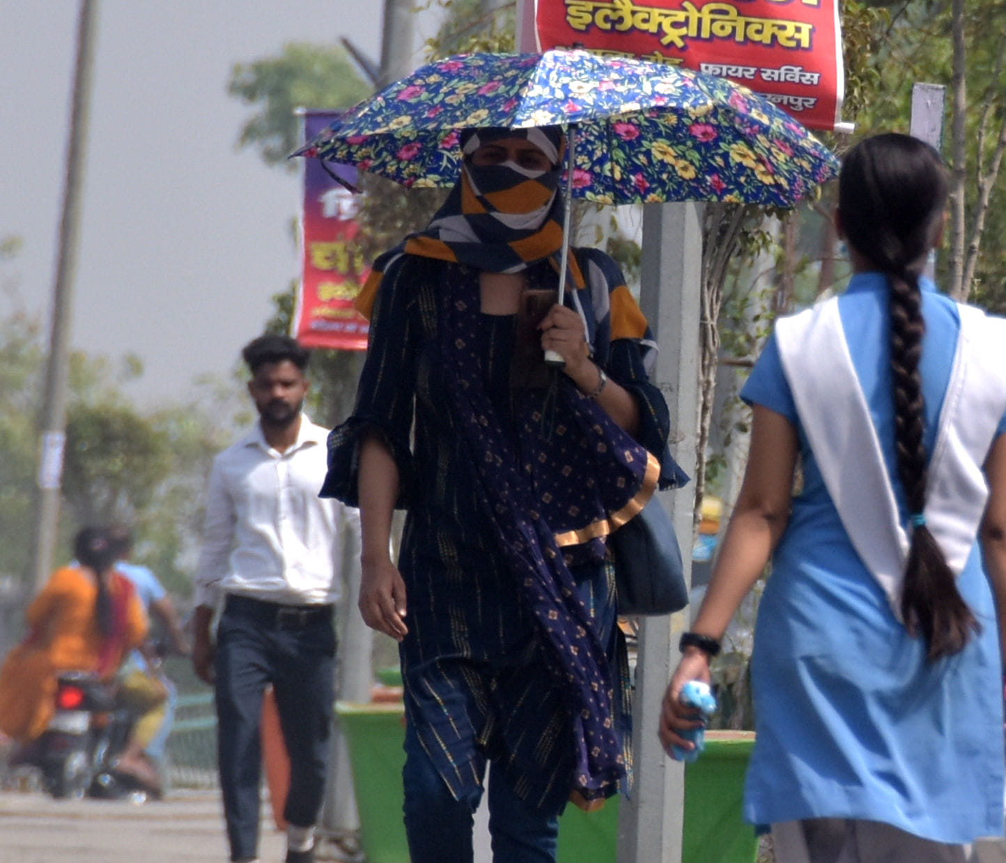 सहारनपुर में बढ़ती गर्मी के चलते कोर्ट रोड़ पर चेहरा ढाककर छत्ता लेकर जाती युवती