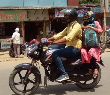 लू से बचने के लिए चेहरा ढके बाइक पर बैठी महिला। संवाद