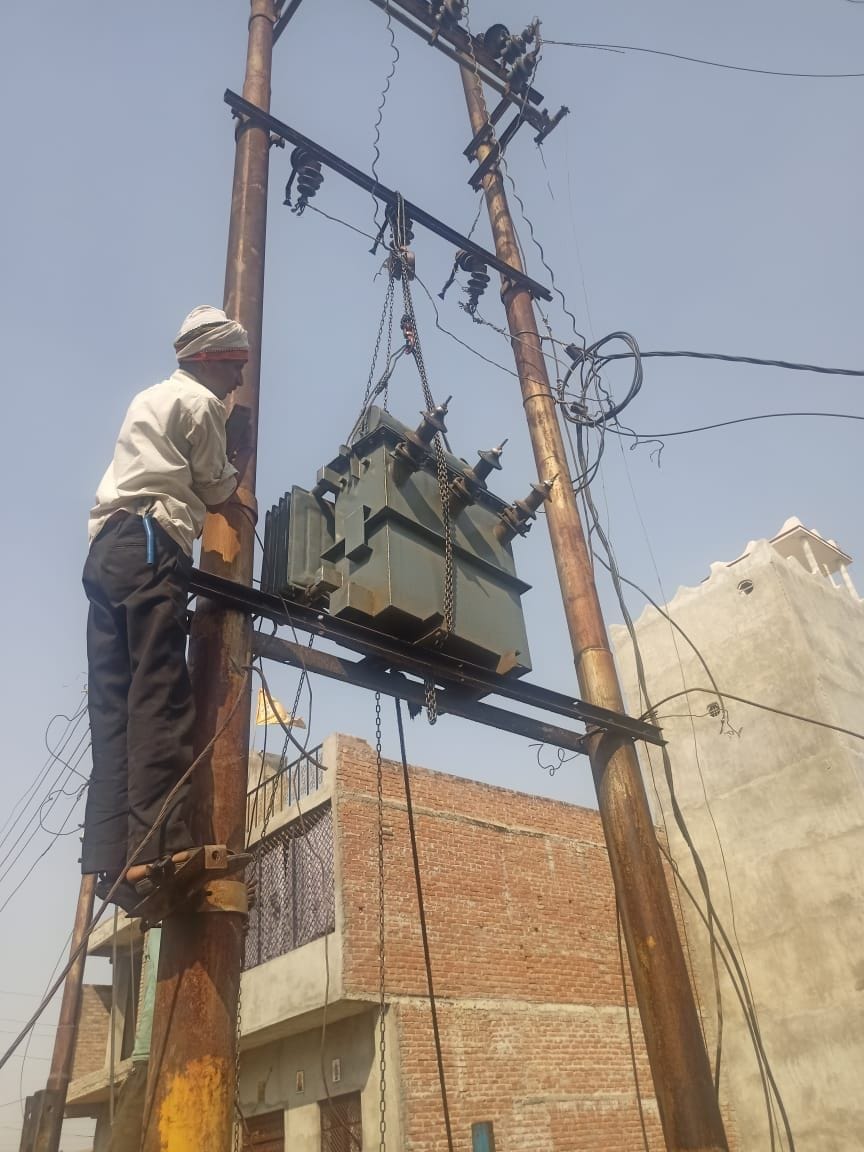  उपभोक्ताओं के घेराव के बाद ट्रांसफार्मर लगाता बिजली कर्मचारी। संवाद