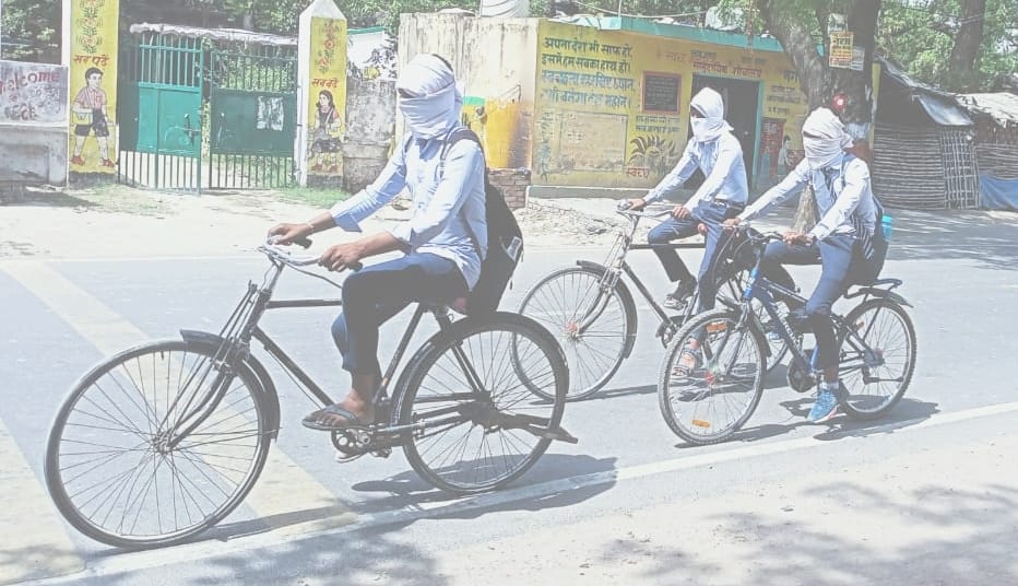 ज्ञानपुर नगर में गर्मी से बचने के लिए चेहरा ढंककर स्कूल जाते छात्र। संवाद