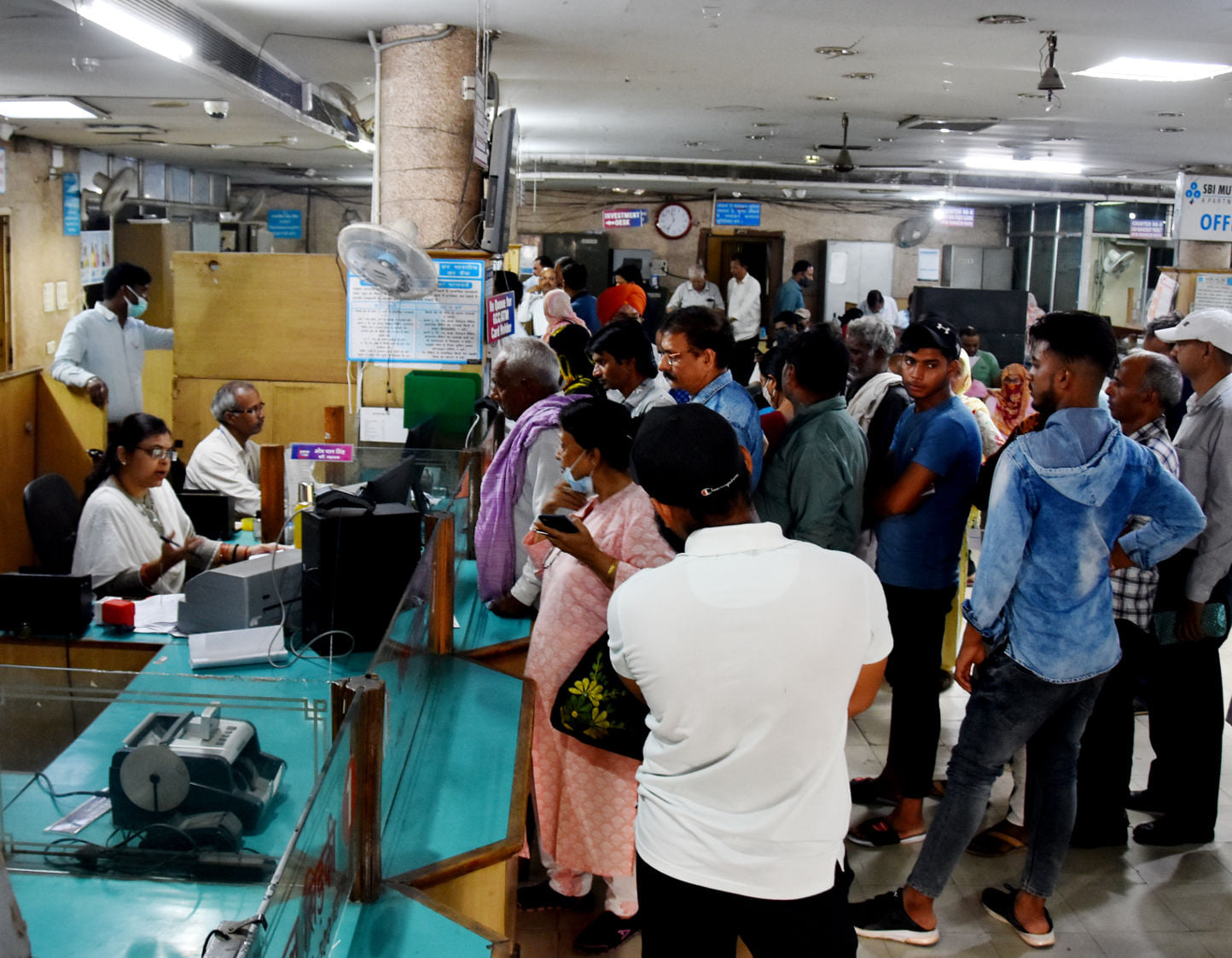 कोर्ट रोड स्थित बैंक में बिना मास्क के काम करते कर्मी व बिना मास्क के लाइन में लगे लोग
