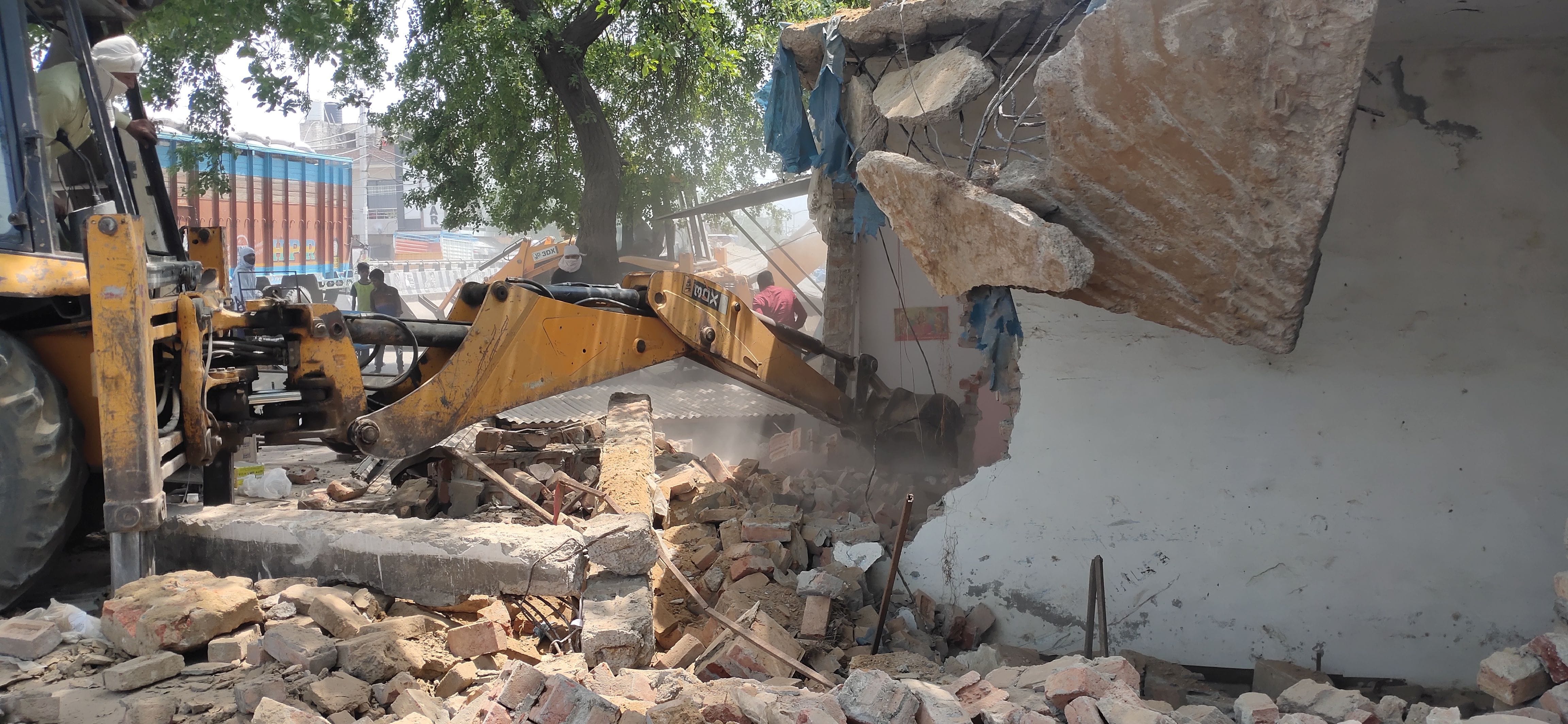 टोहाना में दुकानों को बुलडोजर से ढहाता चालक। टोहाना में दुकानों को बुलडोजर से ढहाता चालक।