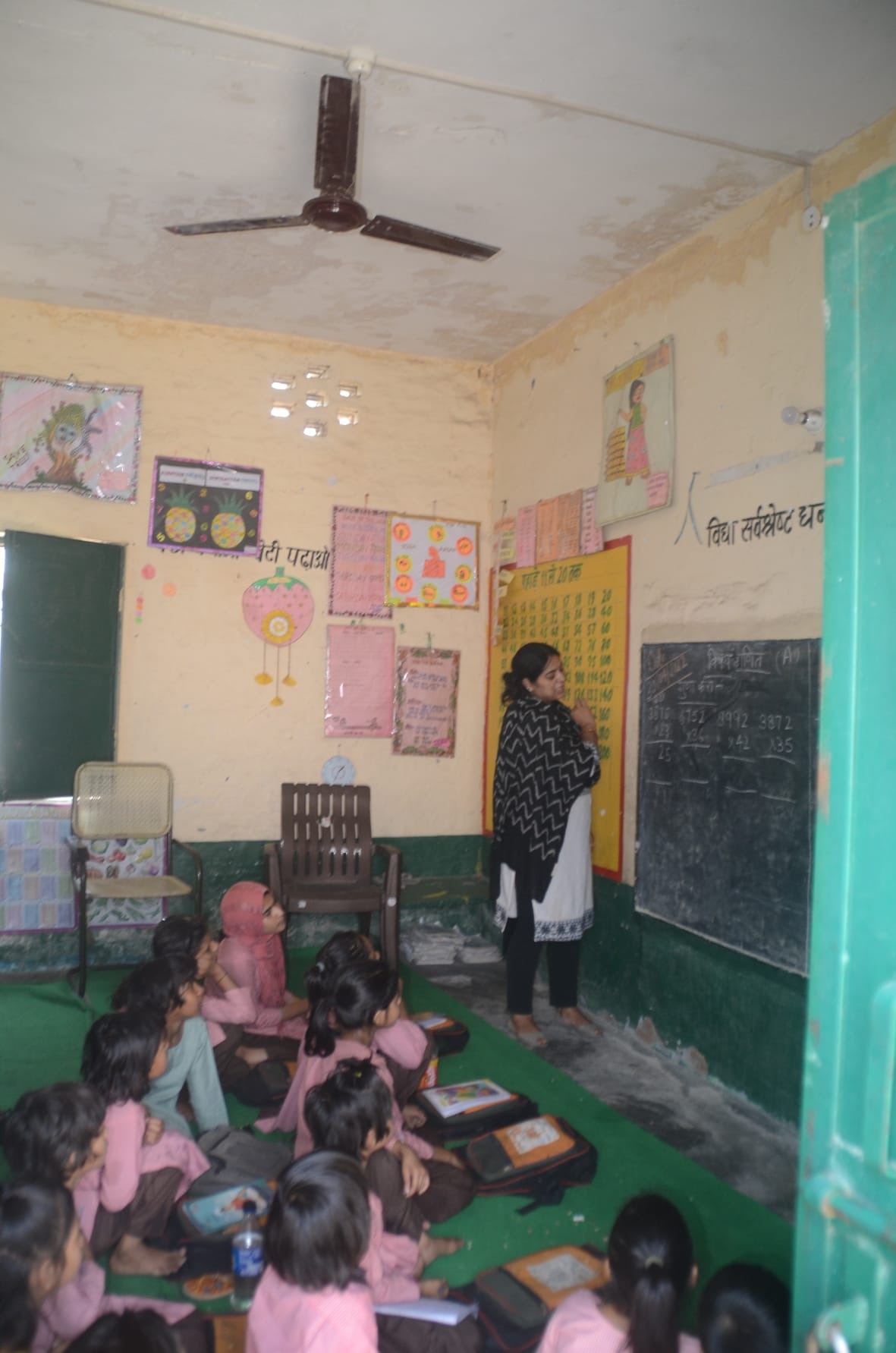 बागपत के निवाड़ा गांव स्थित प्राथमिक विद्यालय में बंद पड़ा पंखा बच्चों को पढ़ाती अध्यापिका