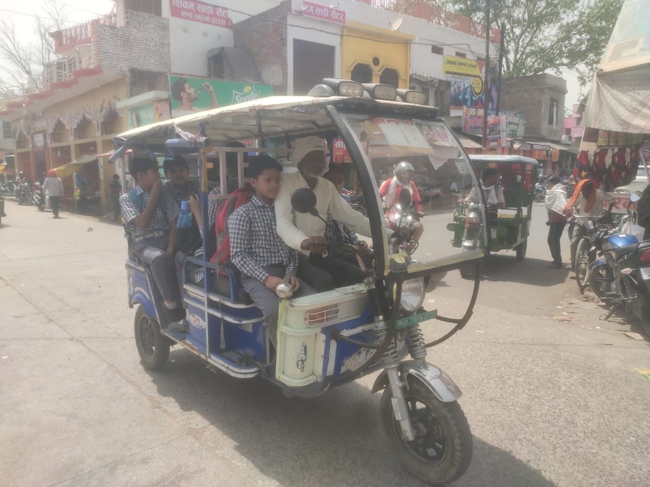 ई-रिक्शे में बैठकर जाते बच्चे। संवाद