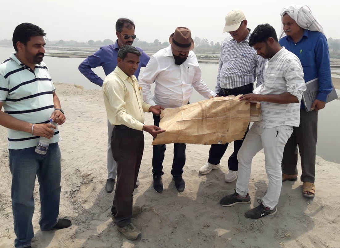 यमुना खादर मे सरकारी भूमि की पैमाईश के लिए नक्शा देखती लखनऊ से आई राजस्व विभाग की टीम
