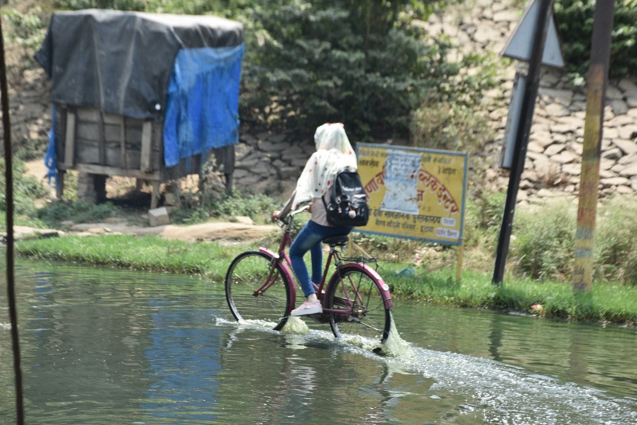 जलभराव से गुजरती साइकिल सवार छात्रा। संवाद