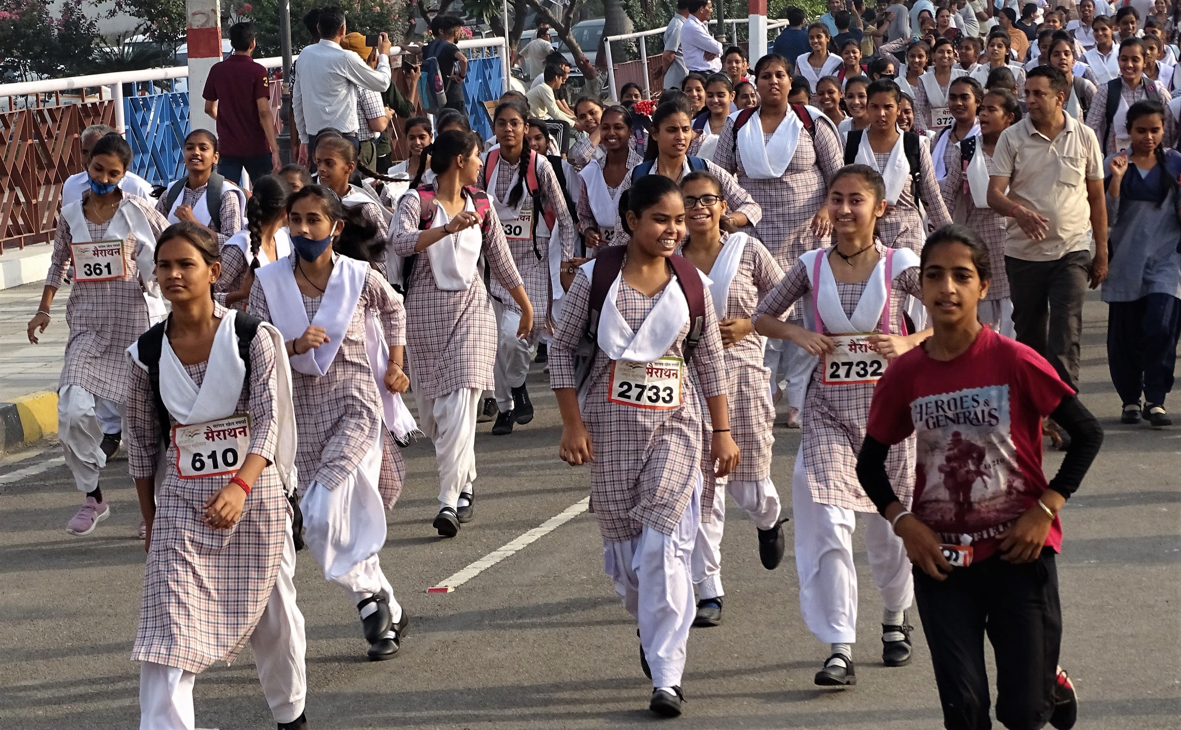 मैराथन में कंधे पर बैग लेकर दौड़ती छात्राएं। संवाद मैराथन में कंधे पर बैग लेकर दौड़ती छात्राएं। संवाद