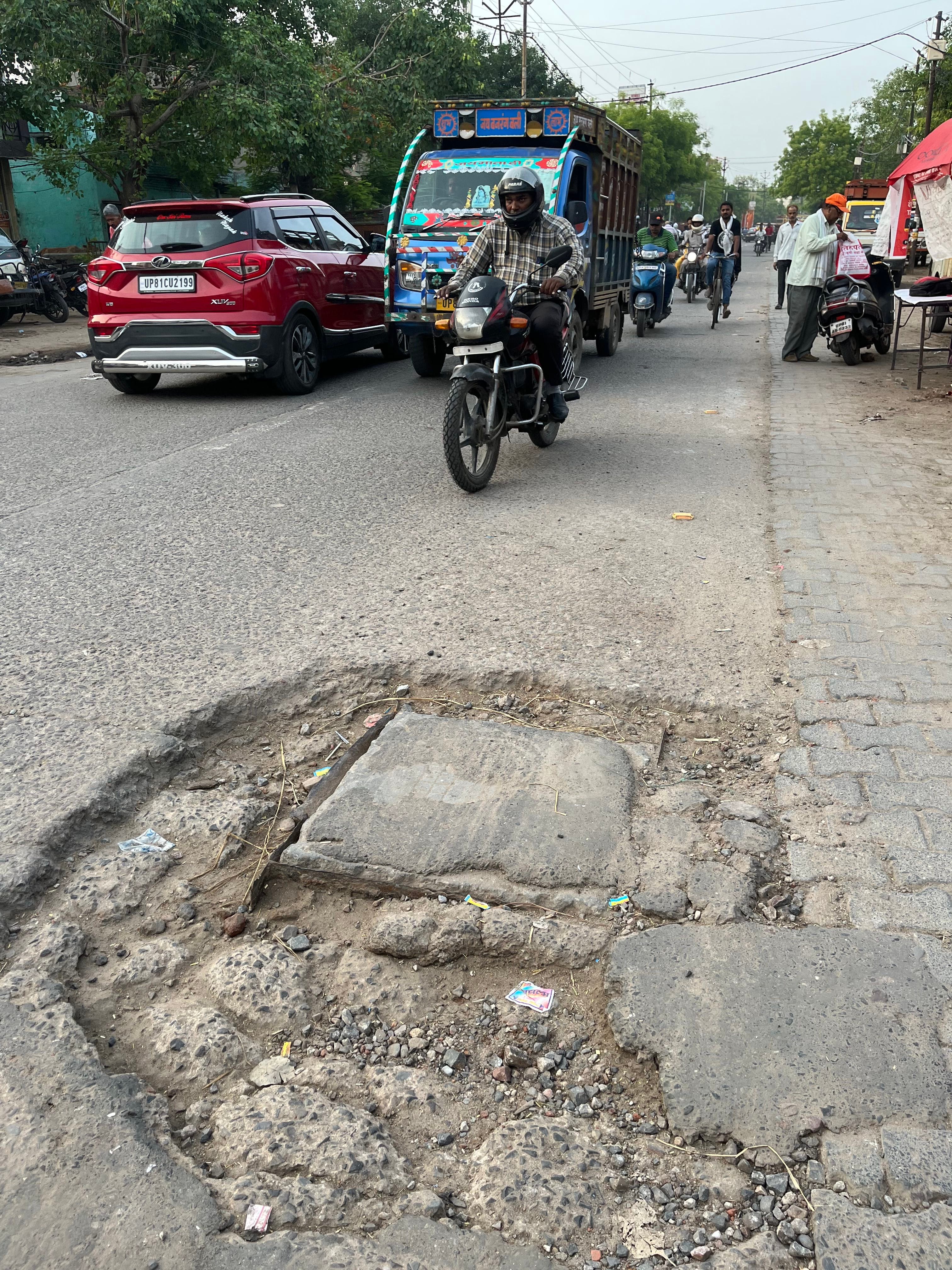 आगरा रोड निकट सासनी गेट चौराहा पर सड़क पर गड्ढा।