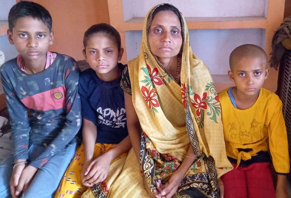 गमगीन माहौल में बैठी मृतक की पत्नी व बच्चे।