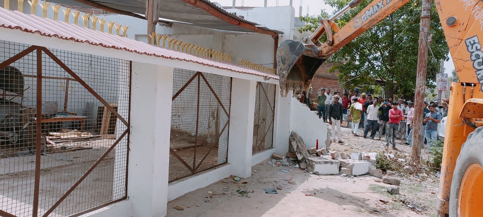 सफीपुर में बुलडोजर से तोड़ी जाती मैरिज लॉन की चारदीवारी। संवाद