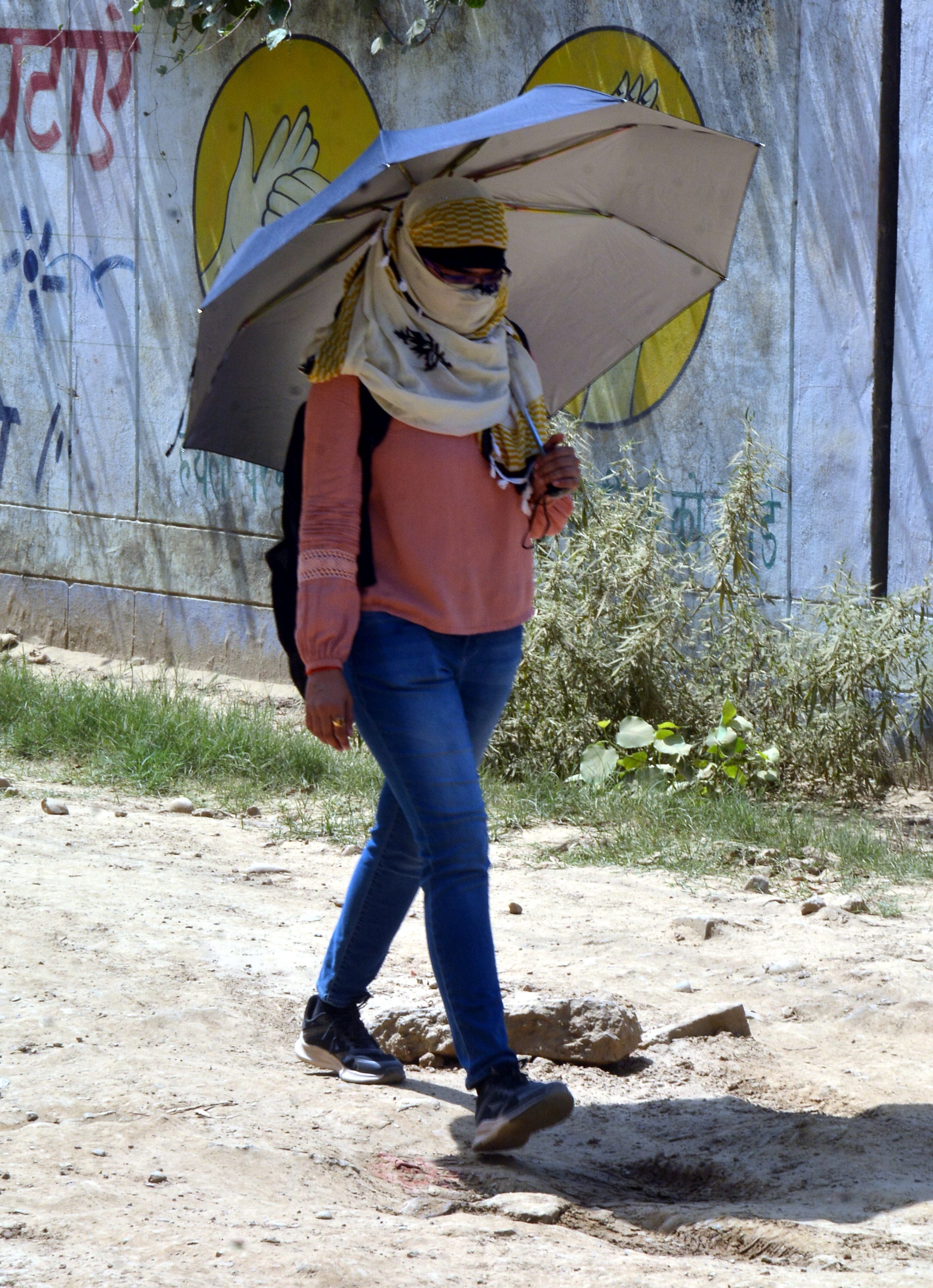 गर्मी में छाता लेकर गंतव्य को जाती युवती। गर्मी में छाता लेकर गंतव्य को जाती युवती।