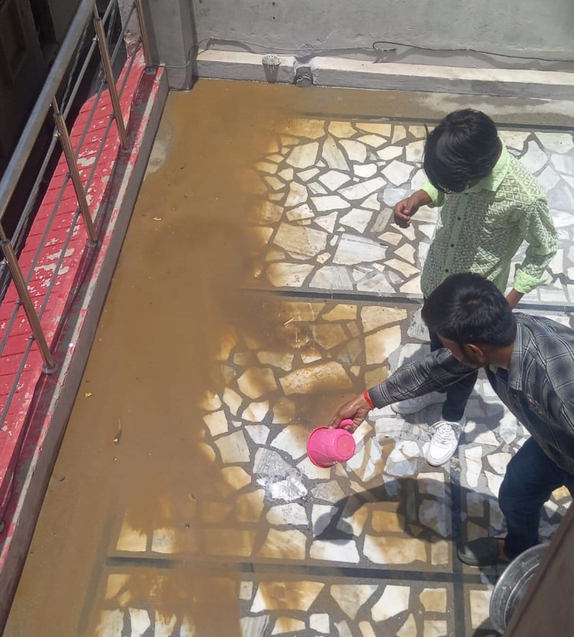 बागपत कोर्ट रोड पर घर की पानी की टंकी से निकाली गई मिट्टी की सफाई करते हुए