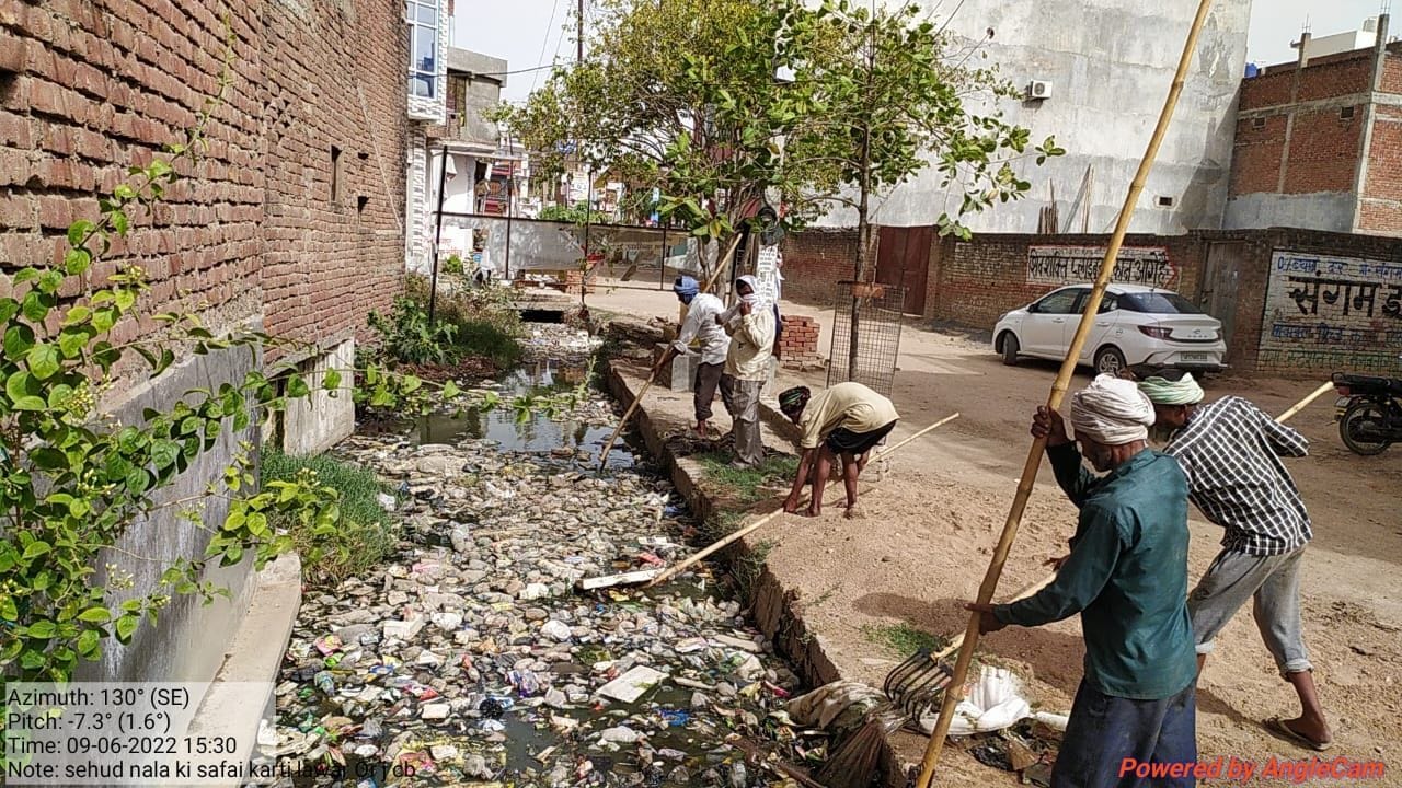   जलनिकासी के लिए अवरोध बने नाले में भरे कूड़े को हटाते मजदूर। संवाद