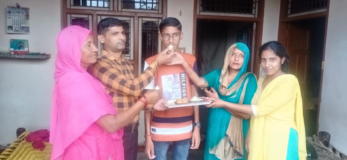 हाई स्कूल में जिले में तीसरा स्थान पाने वाले मयंक को मिठाई खिलाते परिजन
