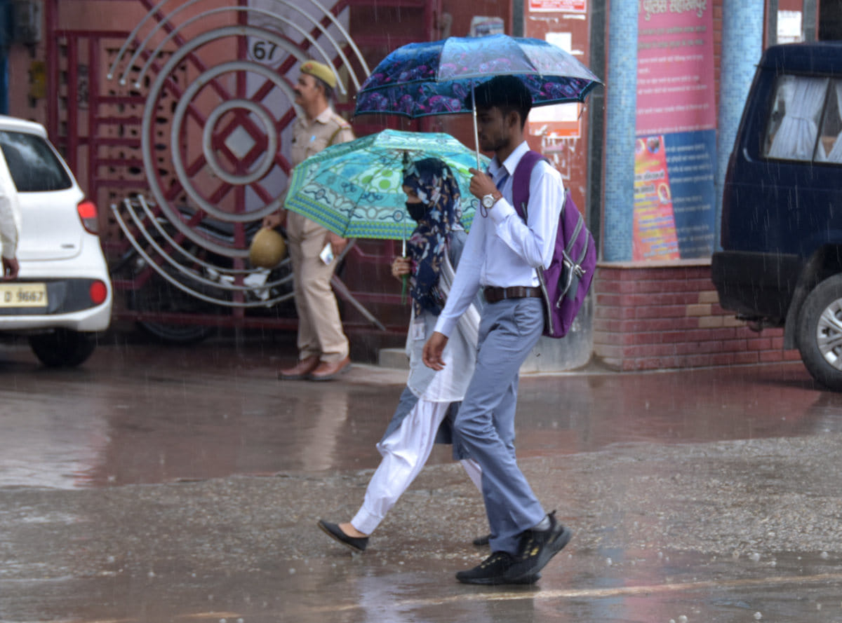 सहारनपुर में हुई बरसात में छात्ता लेकर जाते छात्र छात्रा