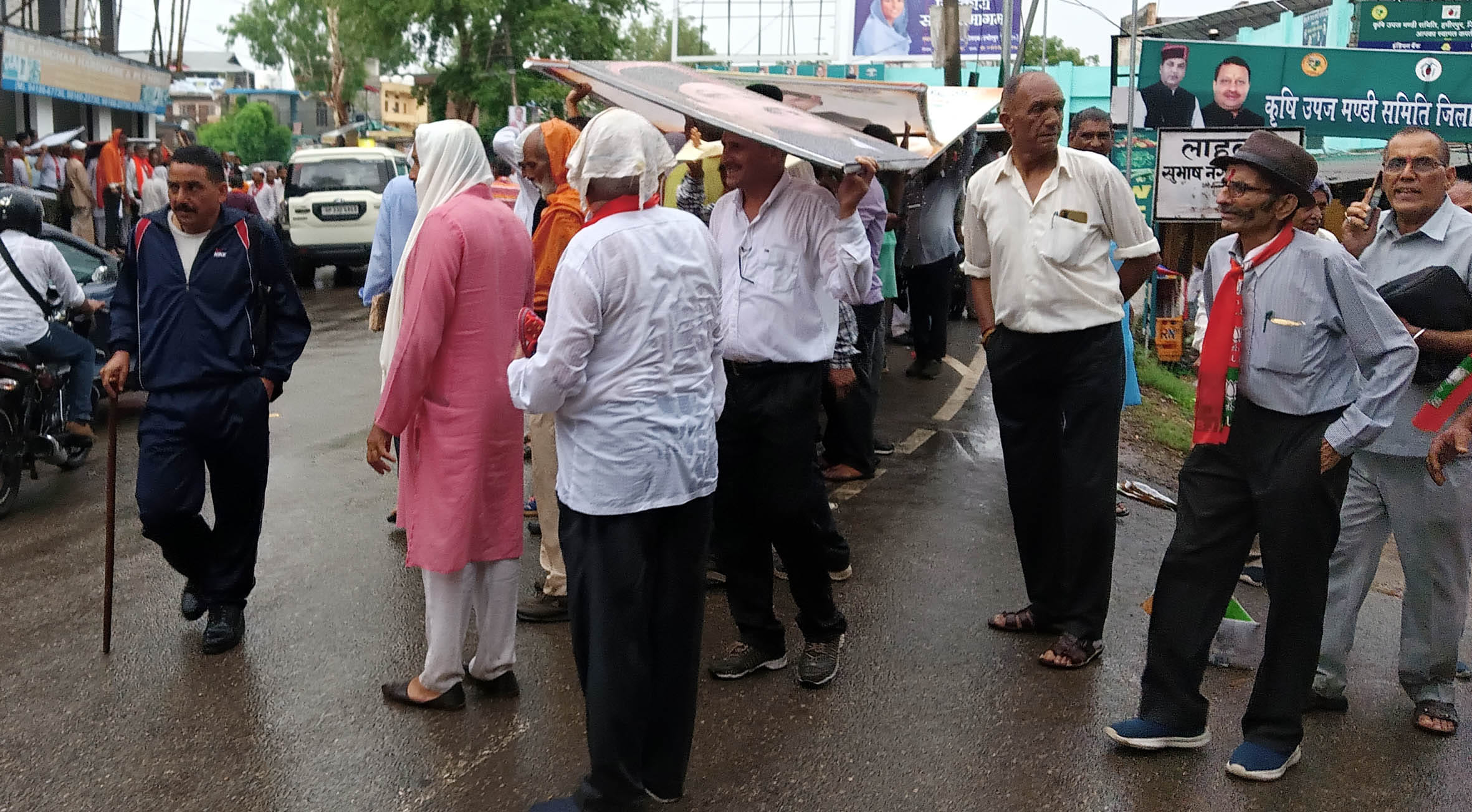 हमीरपुर में त्रिदेव सम्मेलन के बाद बारिश से बचने के लिए होर्डिंग्स सिर पर रखकर घर जाते त्रिदेव।