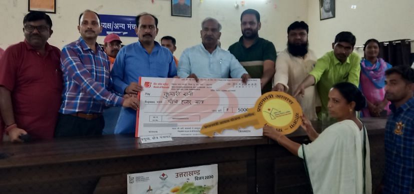 गदरपुर में प्रधानमंत्री आवास योजना ग्रामीण के लाभार्थी को प्रतीकात्मक चेक व चाबी सौंपते विधायक 