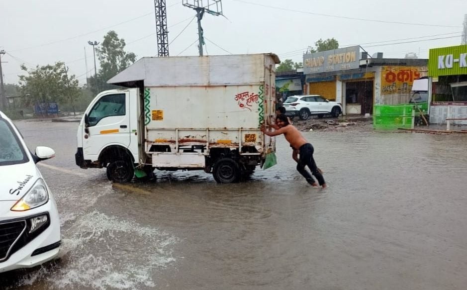 राई जीटी रोड पर पानी से भरी सड़क पर बंद गाड़ी को धक्का लगाते युवक। संवाद राई जीटी रोड पर पानी से भरी सड़क पर बंद गाड़ी को धक्का लगाते युवक। संवाद