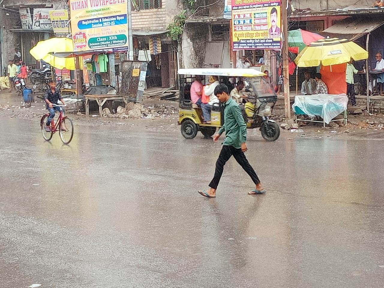 बारिश के दौरान नगर के चित्तू पांडेय चौराहा पर भींगते हुए अपने गंतव्य को जाता किशोर।