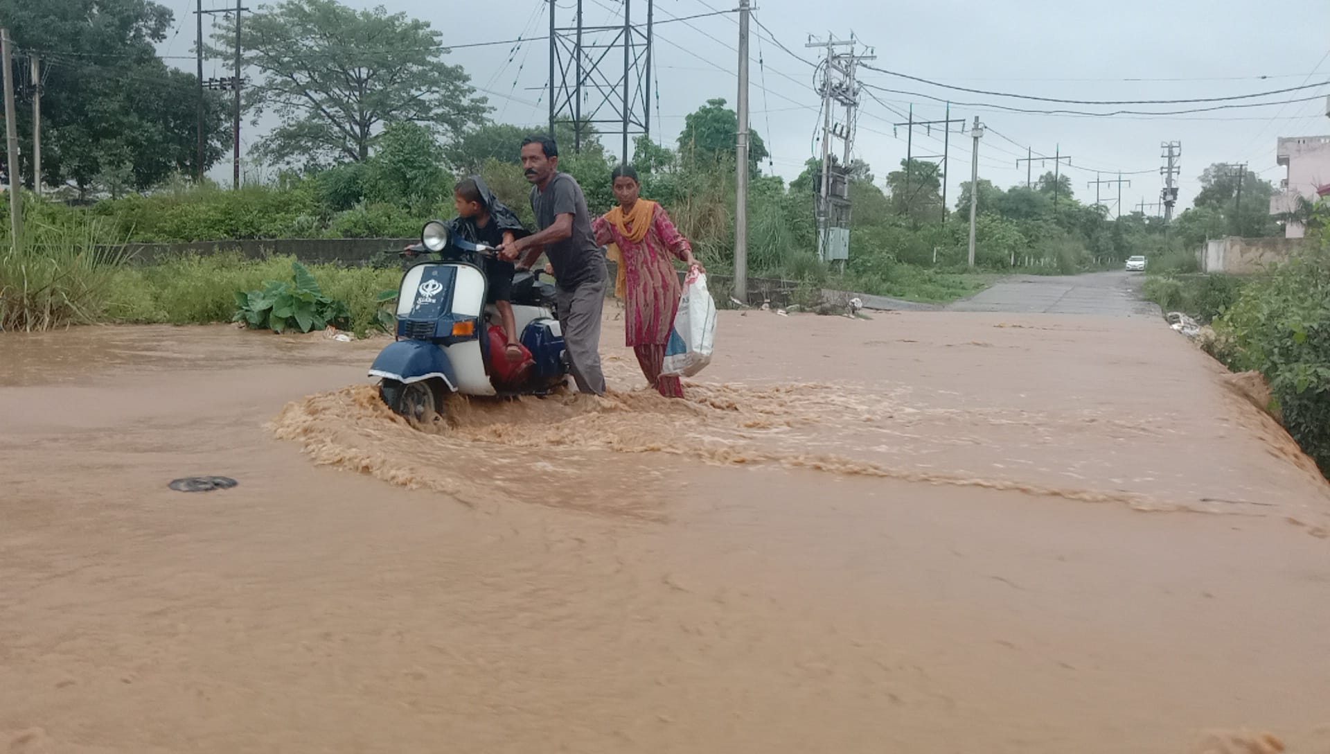 शहर के ड्रीमलैंड पार्क के पास कठुआ खड्ड के तेज बहाव को पार करता परिवार। संवाद शहर के ड्रीमलैंड पार्क के पास कठुआ खड्ड के तेज बहाव को पार करता परिवार। संवाद
