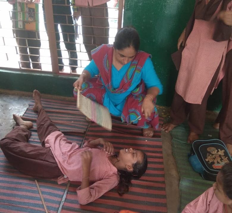 गर्मी से बेहोश हुई छात्रा दीक्षा को पंखा करतीं शिक्षिका मीना गंभीर। संवाद गर्मी से बेहोश हुई छात्रा दीक्षा को पंखा करतीं शिक्षिका मीना गंभीर। संवाद