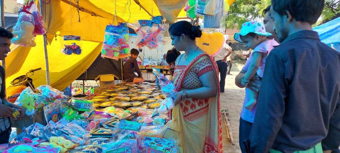 बालैनी के पुरा महादेव मंदिर में लगे मेले में खरीदारी करते श्रद्घालु