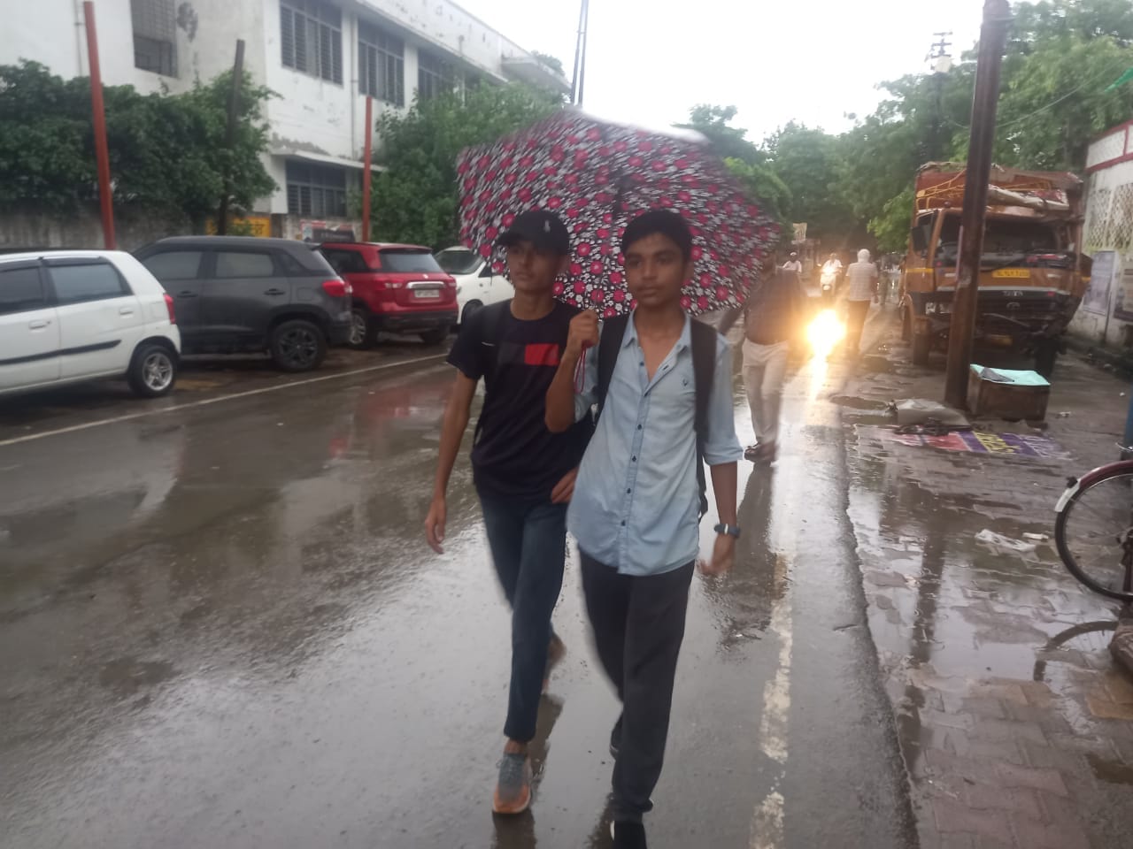 बागपत में बारिश के बीच कोर्ट से गुजरते युवक