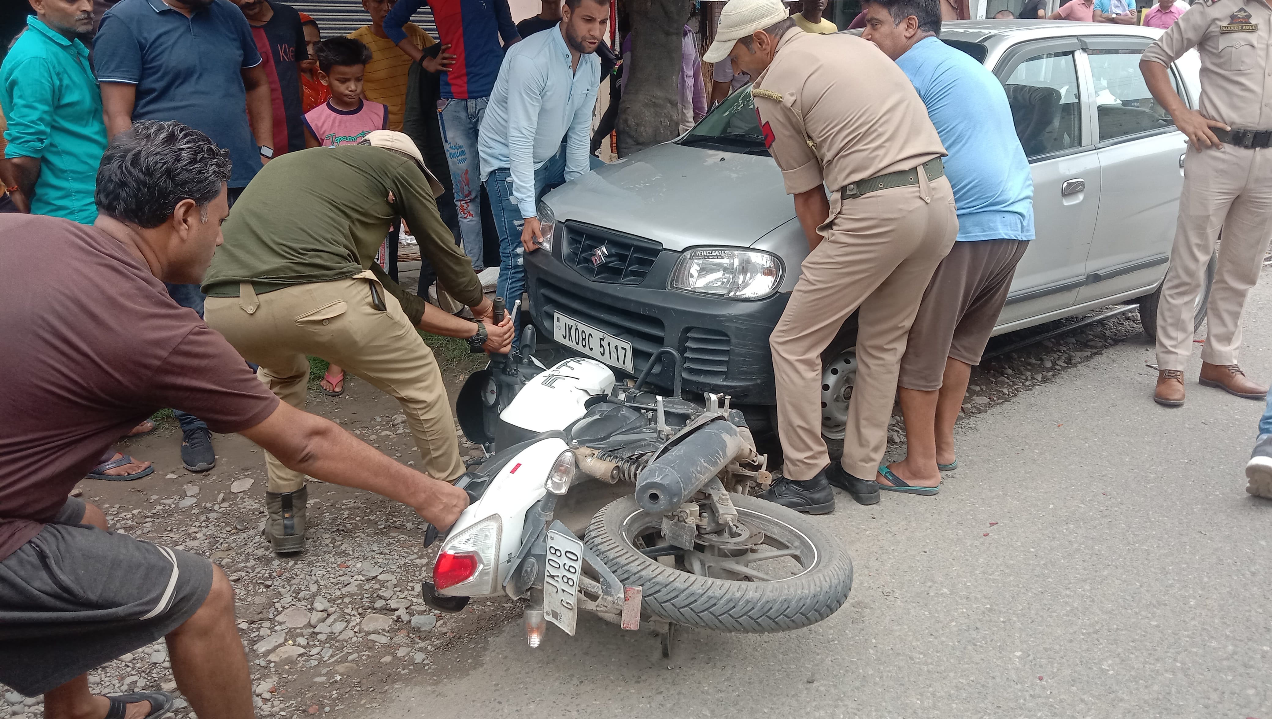 ट्रक की टक्कर लगने के बाद कार के नीचे जा घुसी बाइक को निकालते पुलिसकर्मी व स्थानीय। संवाद ट्रक की टक्कर लगने के बाद कार के नीचे जा घुसी बाइक को निकालते पुलिसकर्मी व स्थानीय। संवाद