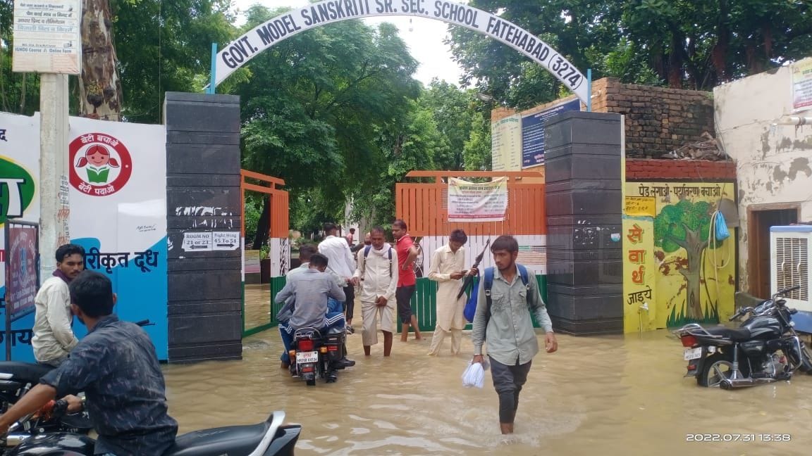 फतेहाबाद के मॉडल संस्कृति स्कूल में भरा पानी और उसमें से निकलते हुए विद्यार्थी।