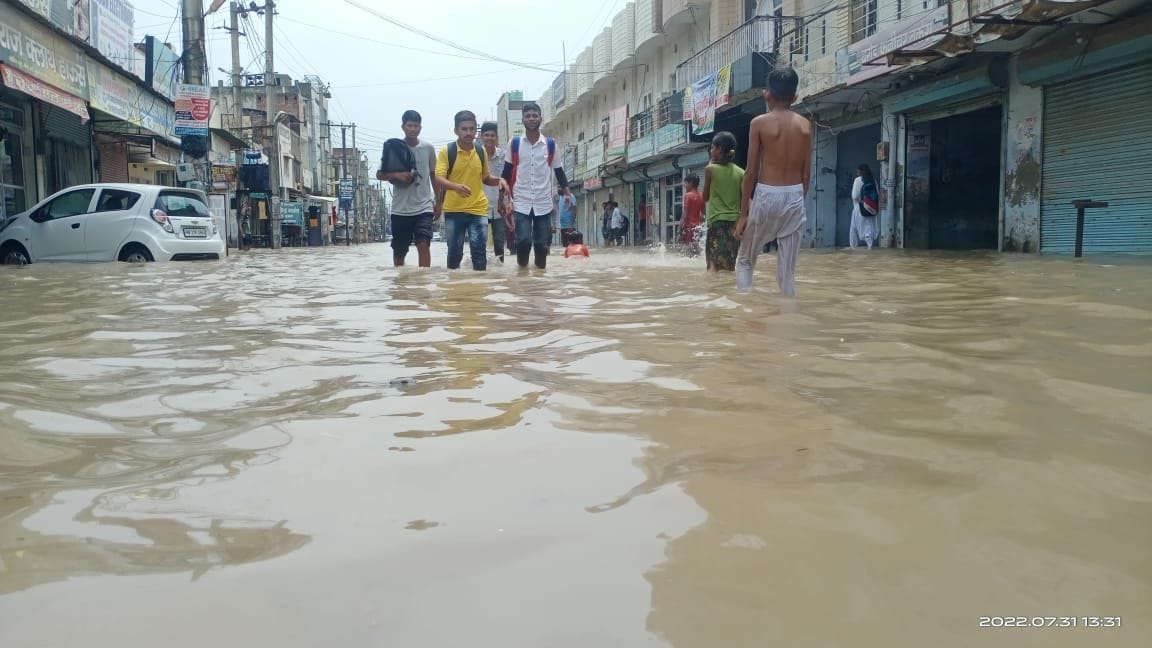 फतेहाबाद के धर्मशाला रोड पर भरे पानी में से निकलकर परीक्षा देने जाते हुए विद्यार्थी।
