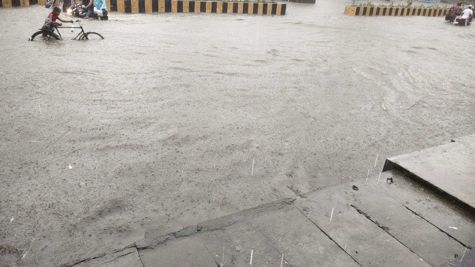 सड़क पर भरे पानी से गुजरता साईकिल सवार सड़क पर भरे पानी से गुजरता साईकिल सवार