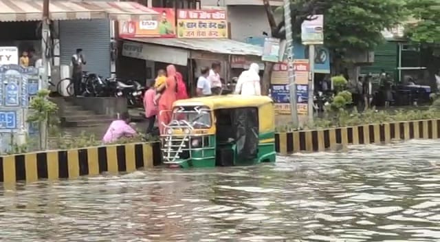 सड़क पर भरे पानी से गुजरता टैंपु सड़क पर भरे पानी से गुजरता टैंपु