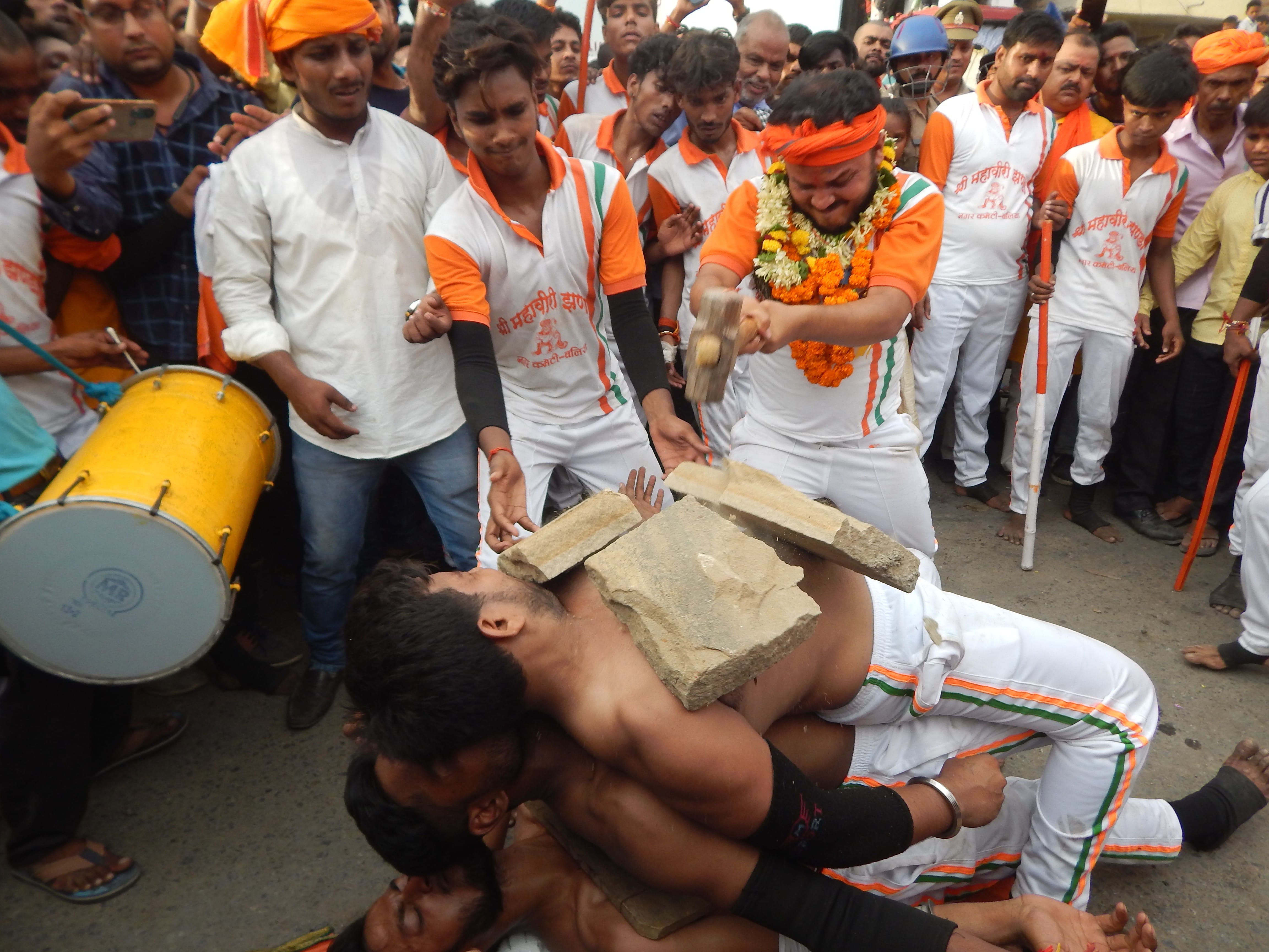 नगर के महावीरी झंडा जुलूस के दौरान करतब के दौरान खिलाड़ी के सीने पर हथौड़ा से पत्थर तोड़ता खिलाड़ नगर के महावीरी झंडा जुलूस के दौरान करतब के दौरान खिलाड़ी के सीने पर हथौड़ा से पत्थर तोड़ता खिलाड़