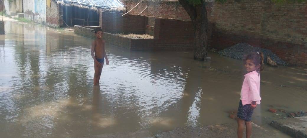 प्रतापपुर गांव में जलभराव से होकर गुजरते बच्चे। संवाद प्रतापपुर गांव में जलभराव से होकर गुजरते बच्चे। संवाद