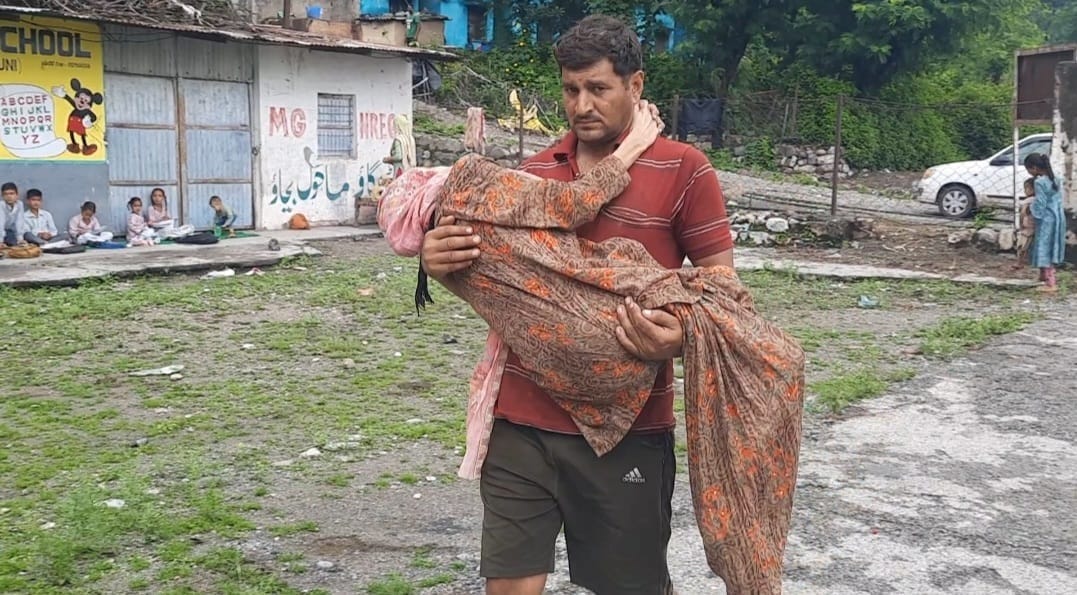 एक बजुर्ग महिला को सुरिक्षत स्थान पर ले जाते हुए युवक। एक बजुर्ग महिला को सुरिक्षत स्थान पर ले जाते हुए युवक।