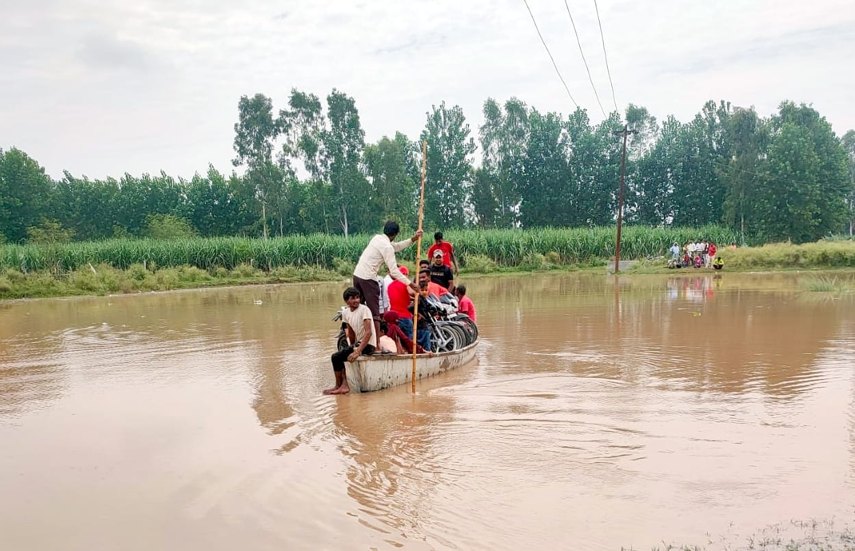 जिनौर के ग्राम रावली में मालन नदी के रपटे पर पानी आने से नाव से जाते लोग। जिनौर के ग्राम रावली में मालन नदी के रपटे पर पानी आने से नाव से जाते लोग।