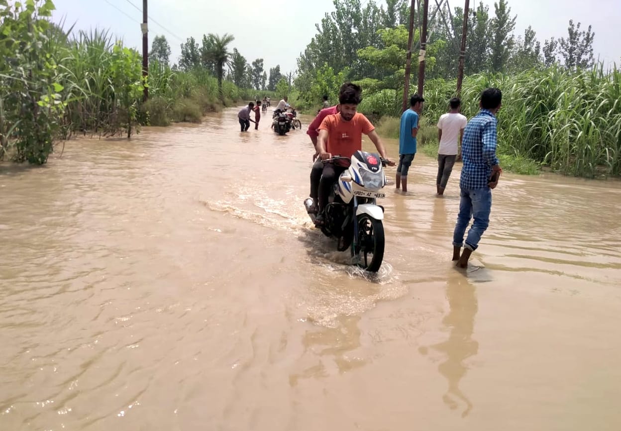 छाछरी मोड के गांव सलेमपुर में सड़क पर भरे गंगा के पानी से गुजरते लोग। छाछरी मोड के गांव सलेमपुर में सड़क पर भरे गंगा के पानी से गुजरते लोग।